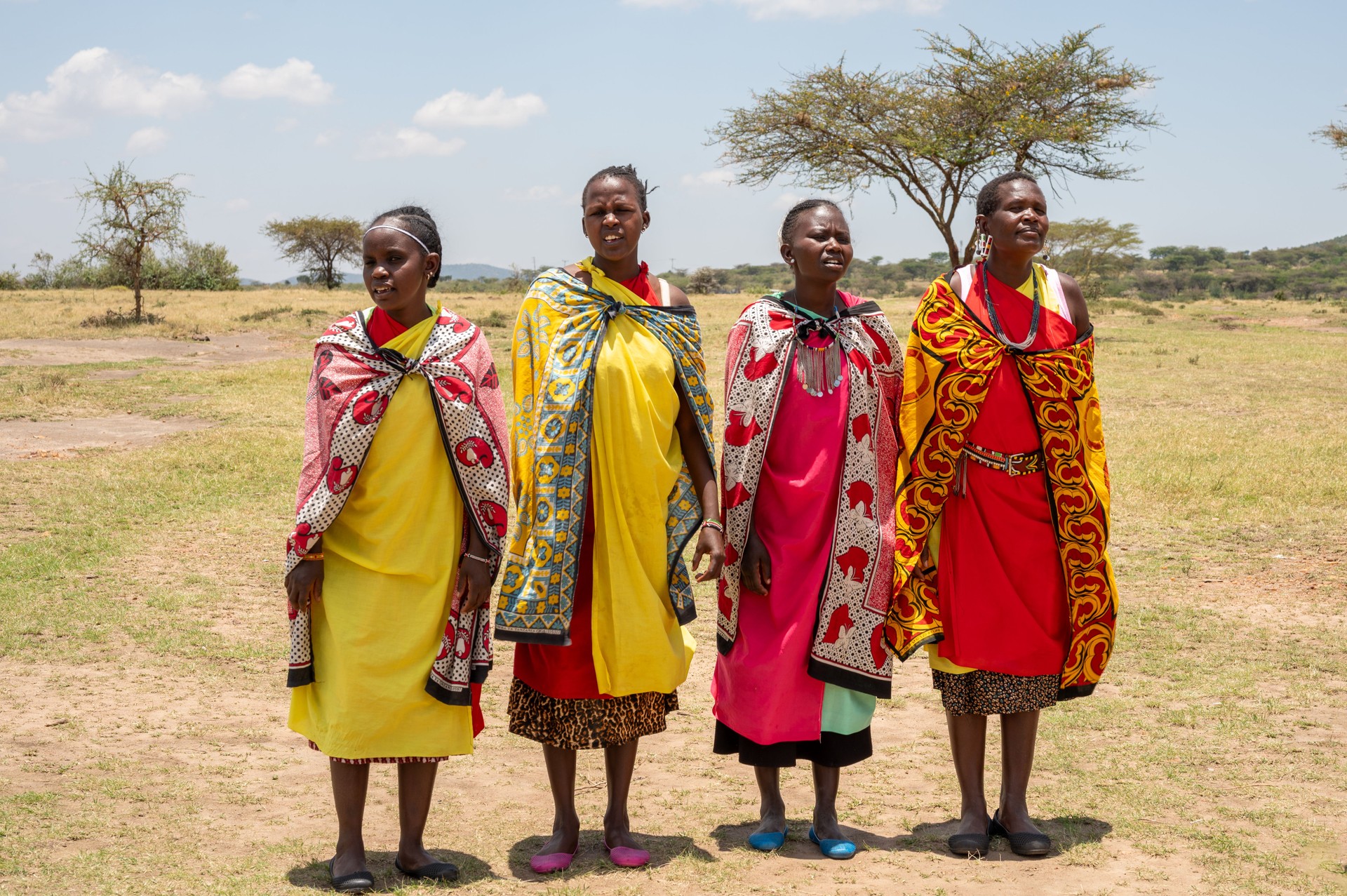 Four masai women singing to welcome tourist to their village