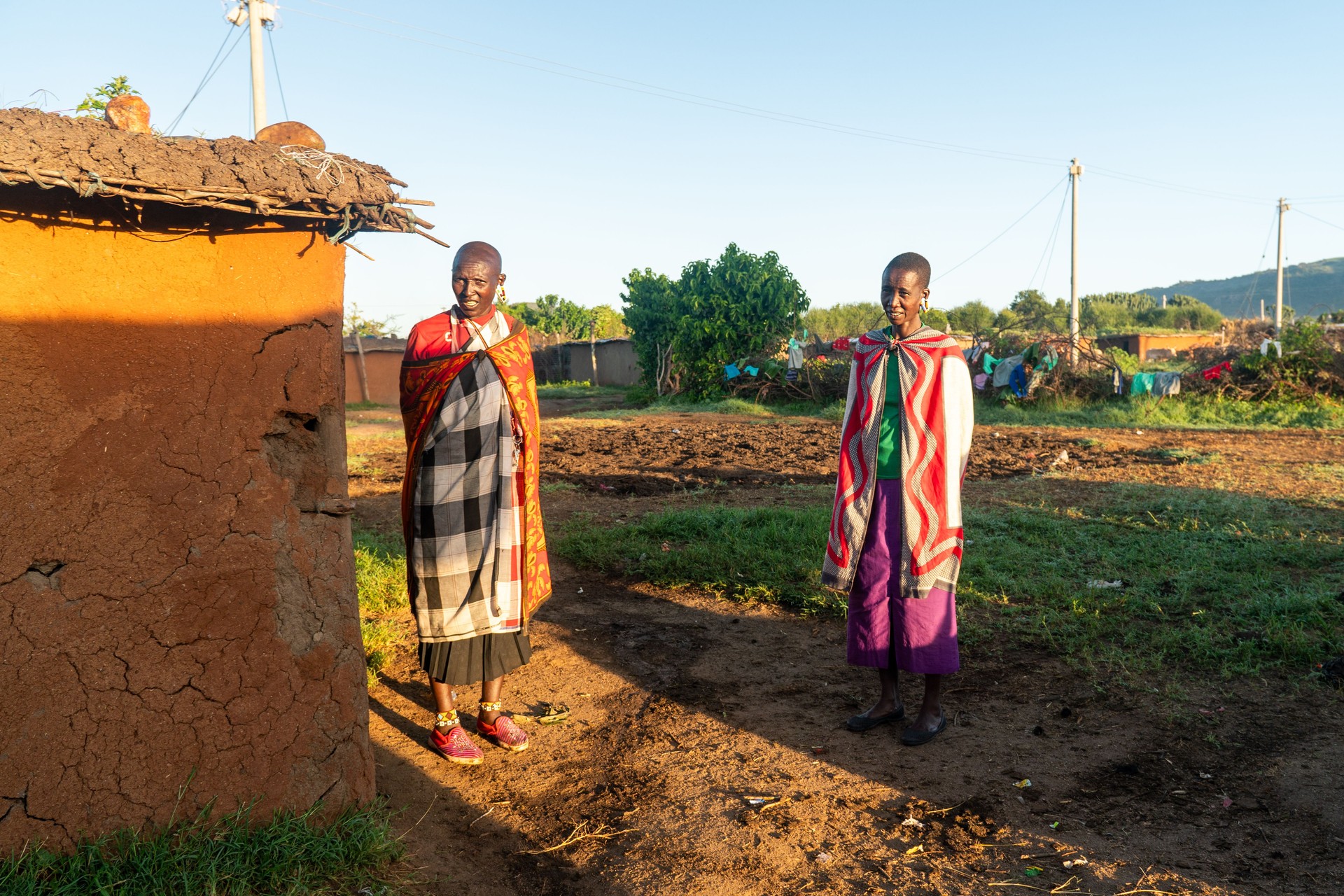 Maasai women stand near clay huts. Traditional life in a Maasai village in East Africa.